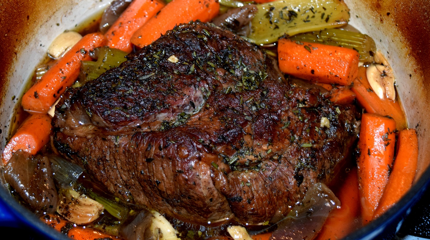 Ultra close-up macro food photography of tender fork-shredded beef pot roast with savory brown herb gravy